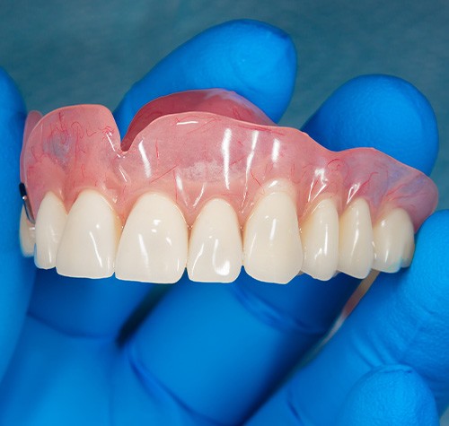 A gloved hand holding an upper denture