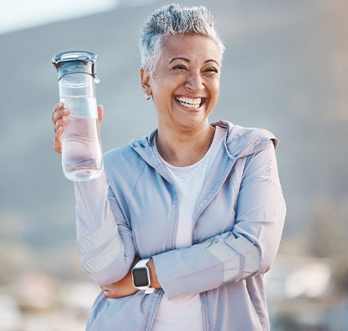 Woman smiling with water bottle on hike outside