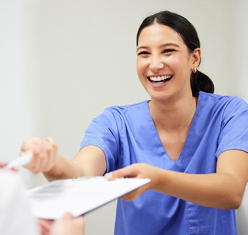 Woman smiling while handing patient form