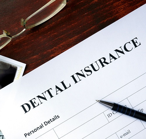 A dental insurance form on a brown desk