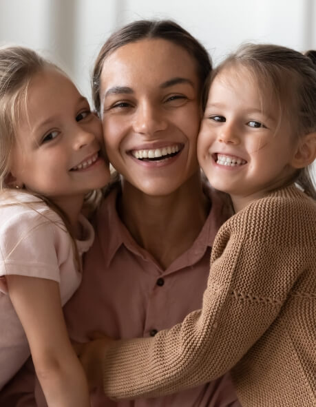Two young girls hugging their mother