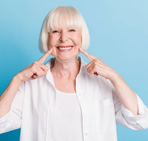 Woman pointing at her smile on a blue background