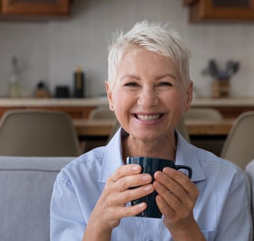Woman enjoying a cup of coffee and smiling
