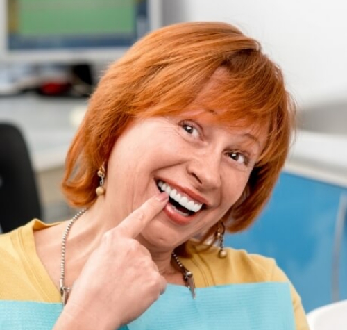 Senior dental patient pointing to her smile