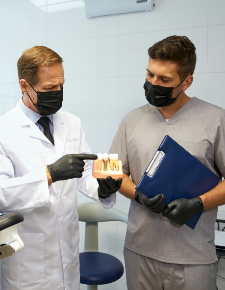 Doctor Maheu looking at a model of a dental implant with another dentist