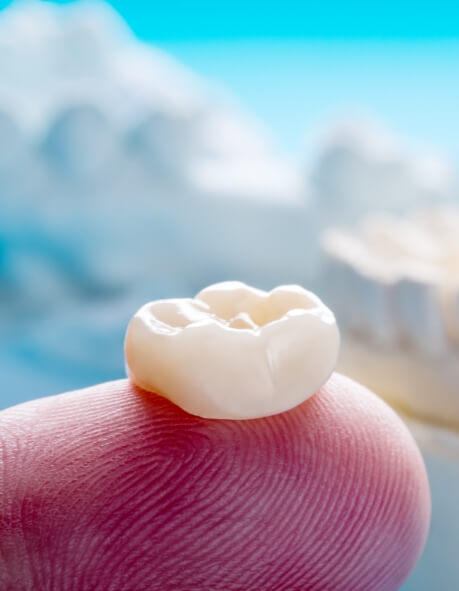 Close up of dental crown resting on finger