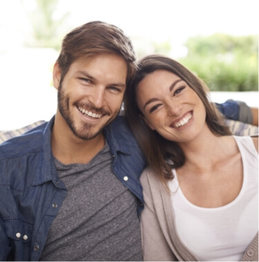 Young man and woman grinning on couch together