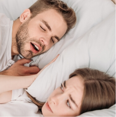 Woman glaring at snoring man next to her