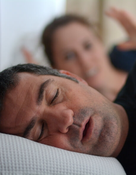 Woman in bed glaring at sleeping man next to her