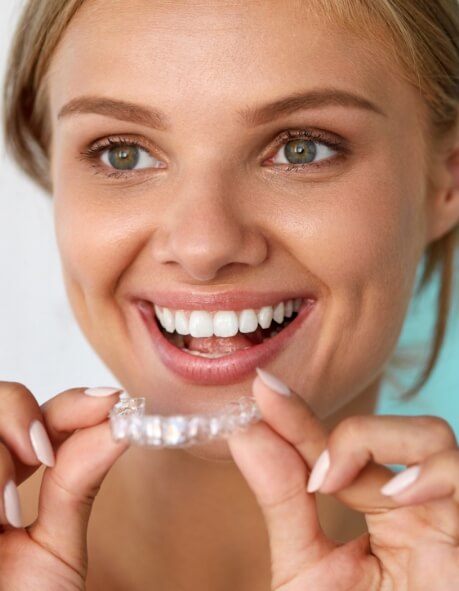 Smiling woman holding a teeth whitening tray