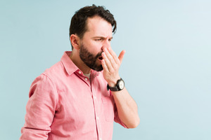 Man with bad breath covering his mouth